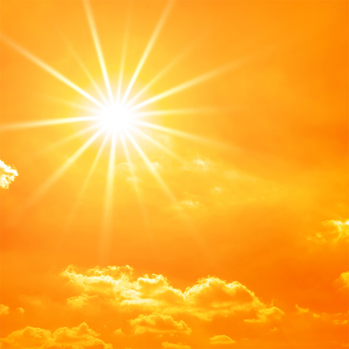 Strahlende Sonne an orange-gelbem Himmel mit kleinen Wolken.