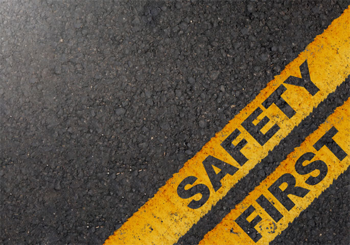 Dunkle Asphaltstraße mit Warnhinweis "SAFETY FIRST"