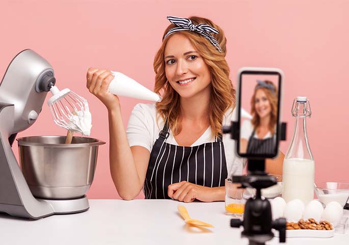 Food Bloggerin backt vor Handy auf Stativ