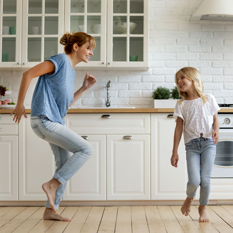 Mutter und Kinder tanzen in moderner Küche.