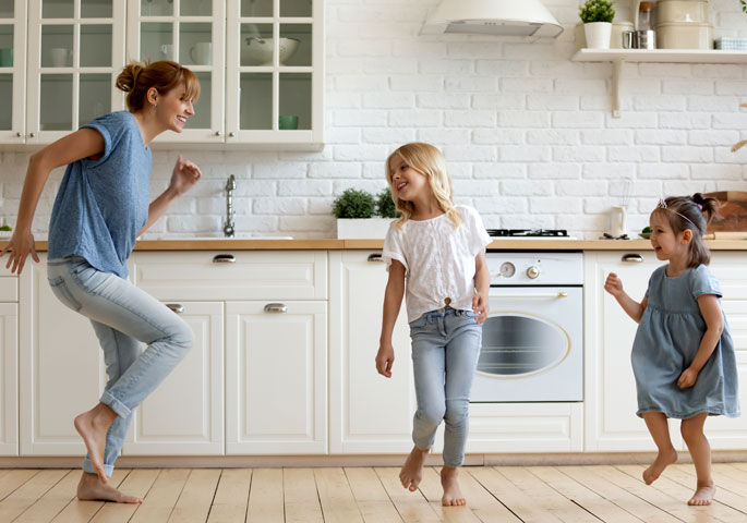 Mutter und Kinder tanzen in moderner Küche.
