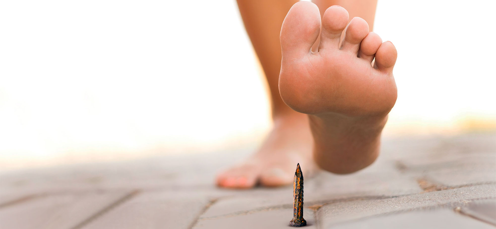 Nakter Fuß kurz vor dem Treten auf einen rostigen Nagel.