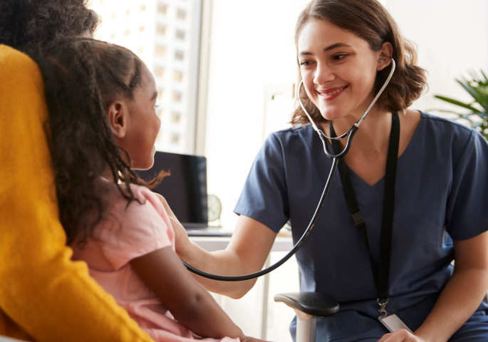 Lächelnde Kinderärztin hört Kind mit Stethoskop ab