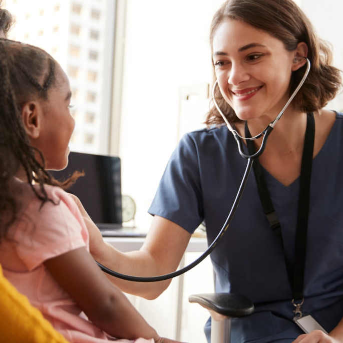 Lächelnde Kinderärztin hört Kind mit Stethoskop ab
