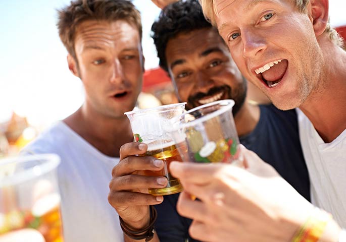Junge Männer auf einem Festival trinken Bier aus Plastikbechern