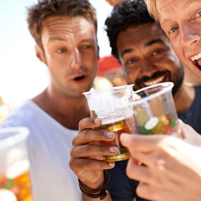 Junge Männer auf einem Festival trinken Bier aus Plastikbechern