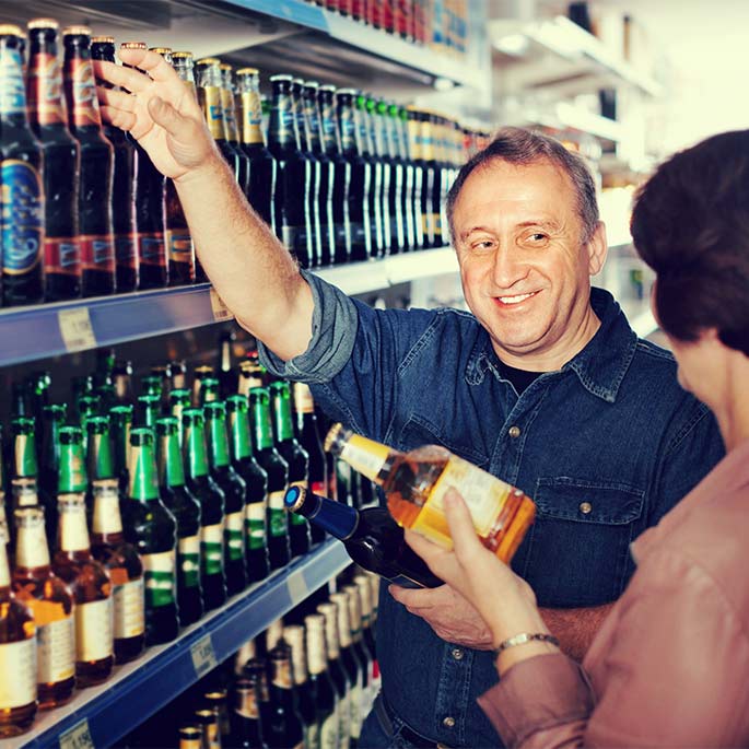 Älteres Paar sucht am Bierregal mit großer Auswahl