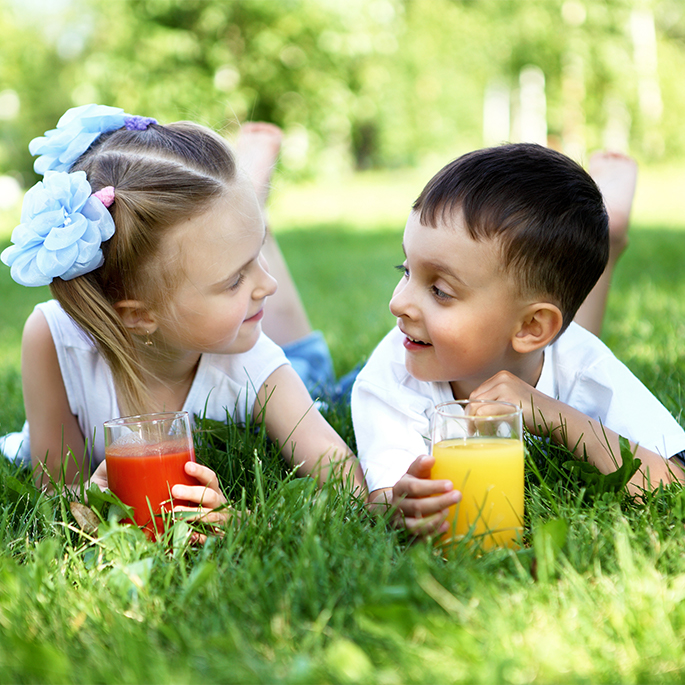Kinder liegen mit Getränk in Wiese.
